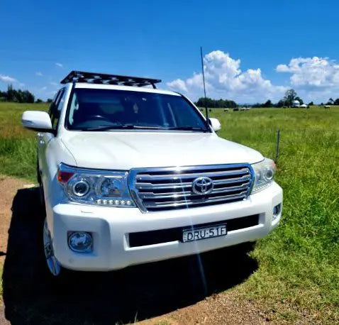 White Toyota Landcruiser standing on a grass field with a GMF4x4 bonnet hinge antenna mount installed